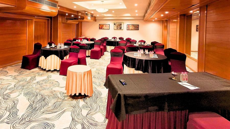 A well-lit conference room at Pride Plaza Ahmedabad, featuring a U-shaped arrangement of tables with red tablecloths, suitable for meetings and presentations.